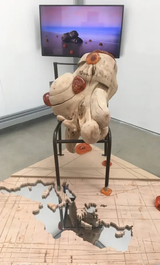 The Testimony of a Refugee I - Question Time, 2017. Exhibited at the Cafe Gallery Project, London, 2018. Various dimensions - cherry tree root, plywood, nine amber resins, school chairs and panel lights. Image courtesy of the artist. 